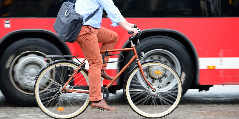 Bicycle commuter riding next to a bus.